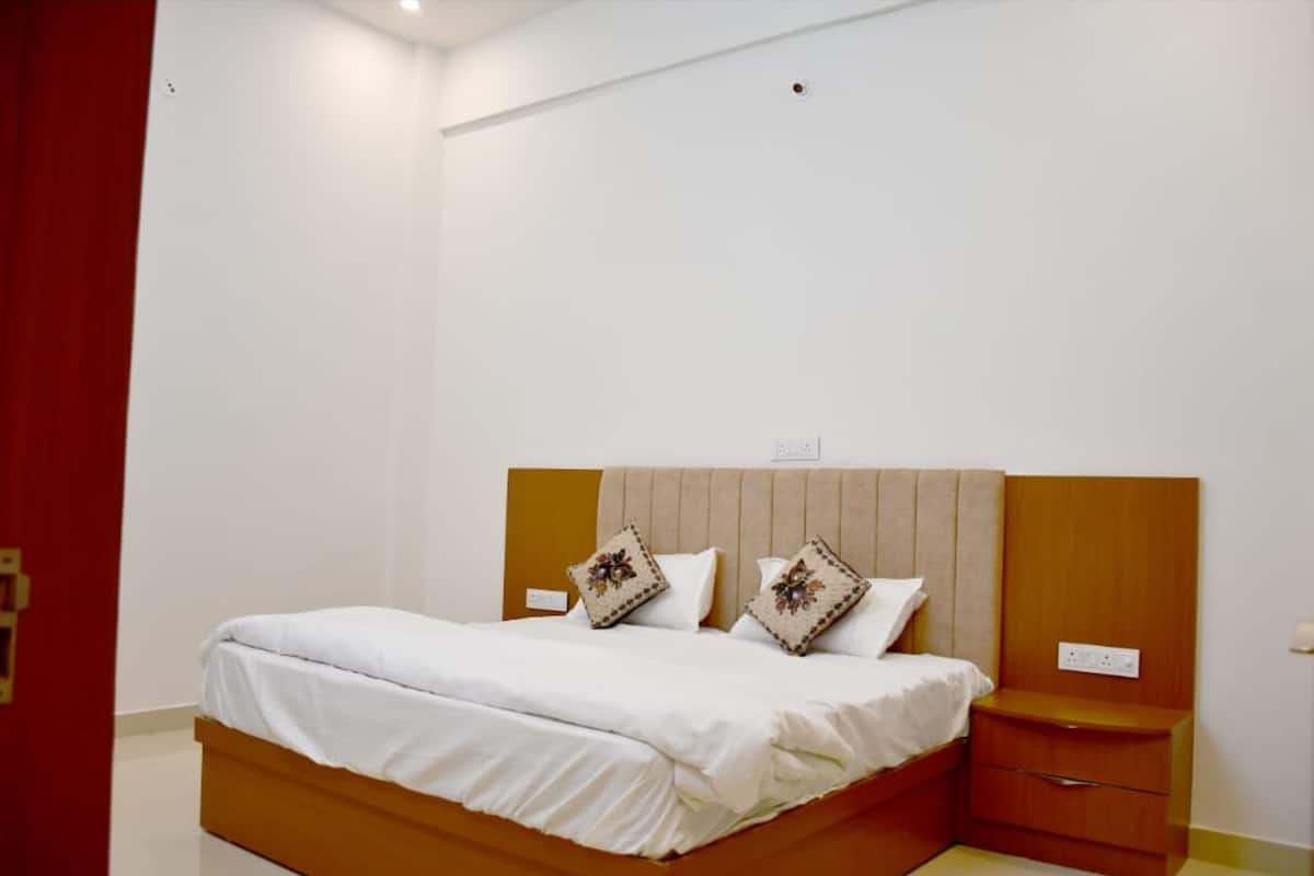 Quarto com cama, duas almofadas, mesa de cabeceira e parede em destaque vermelha.