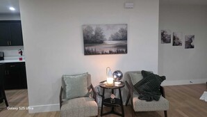 Una sala de estar con dos sillones, una mesita con una lámpara y un globo terráqueo, y un cuadro en la pared.