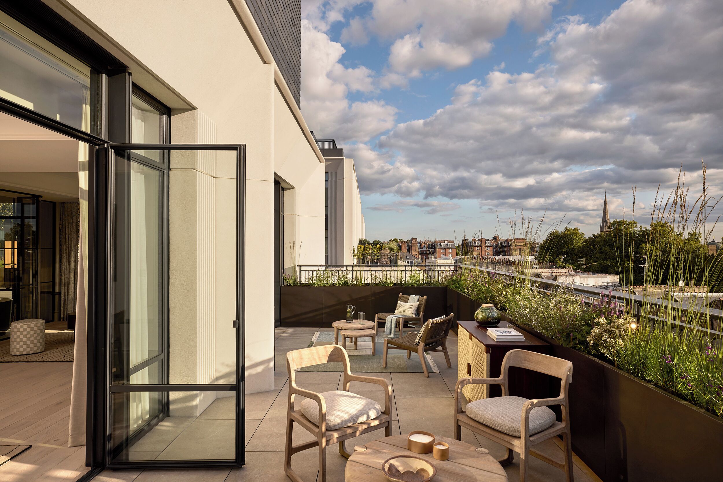 A modern balcony with seating, a glass door, and a view of a cityscape.
