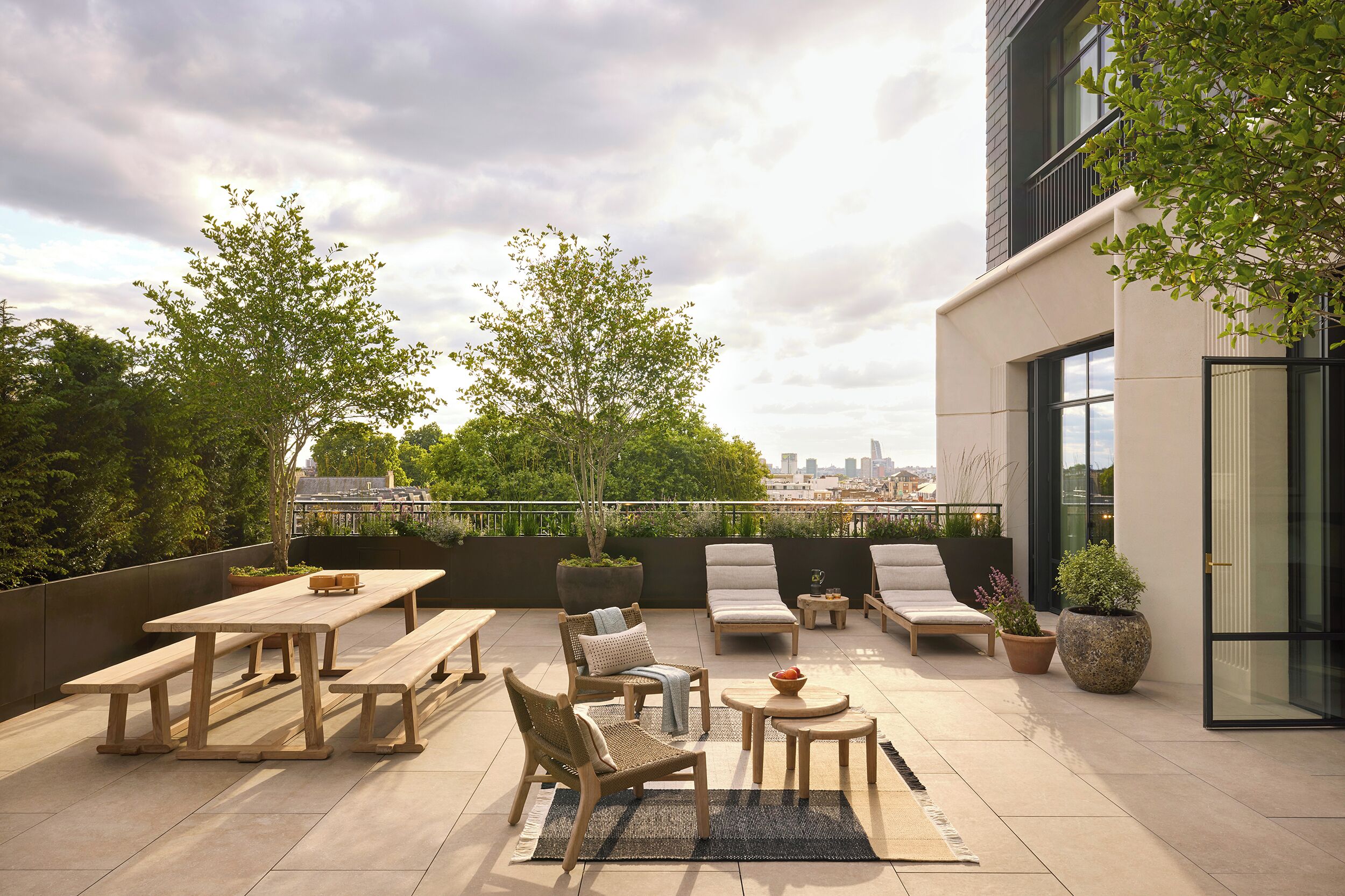 A rooftop patio with outdoor furniture, a dining table, and potted plants.