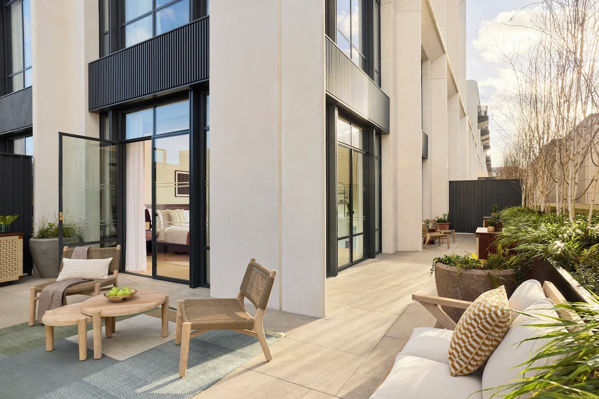 A modern outdoor living area with a sofa, chairs, a table, and potted plants.