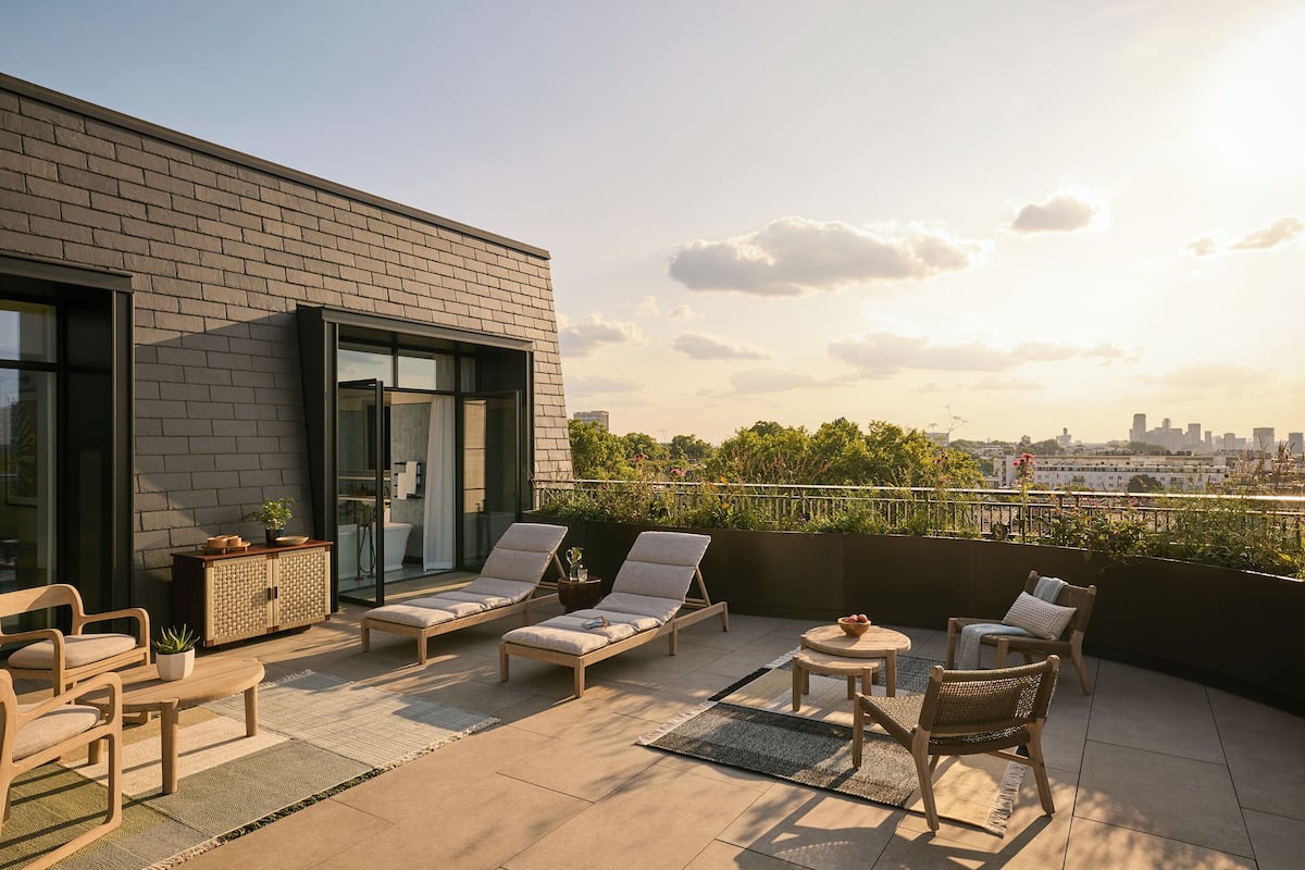 A rooftop terrace with lounge chairs, a small table, and a cabinet.
