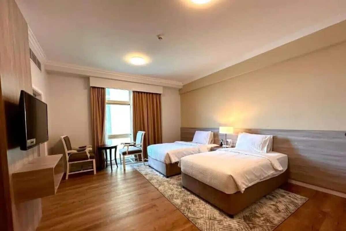 Une chambre d’hôtel avec deux lits, une télévision, un bureau et une chaise.