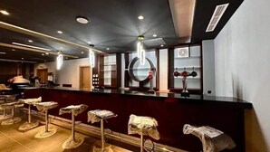 A bar area with a counter, stools, and ceiling lights. - Mirador Hotel (Manama)