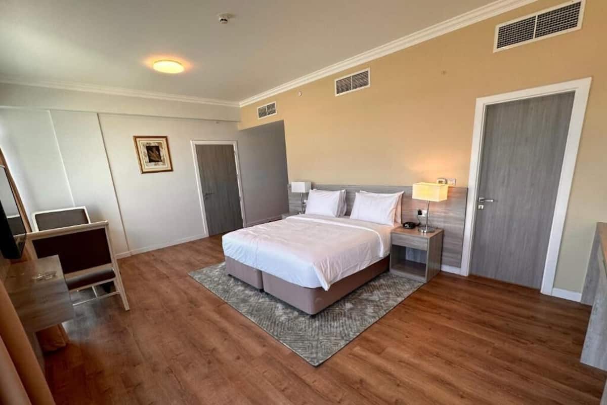 Une chambre à coucher avec un grand lit, une table de chevet avec une lampe, une porte et un petit bureau avec une chaise.