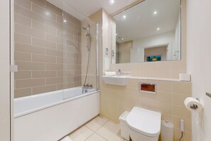 Ein modernes Badezimmer mit Badewanne, Toilette, Waschbecken und Spiegel.