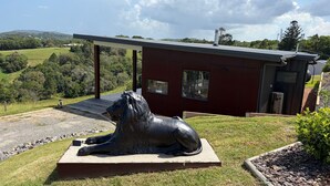Moderni rakennus, jossa on suuri lasi-ikkuna, aurinkopaneeleista koostuva katto ja hevospatsas sen edessä.