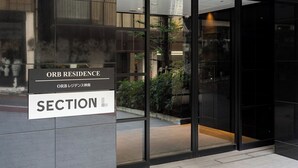 A modern building entrance with glass doors and a sign indicating 'ORB Residence' and 'Section L'. - Section L Residence Shibuya (Tokyo)