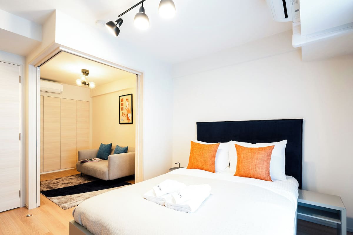 A modern bedroom with a bed, bedside table, and a seating area with a sofa and chairs.
