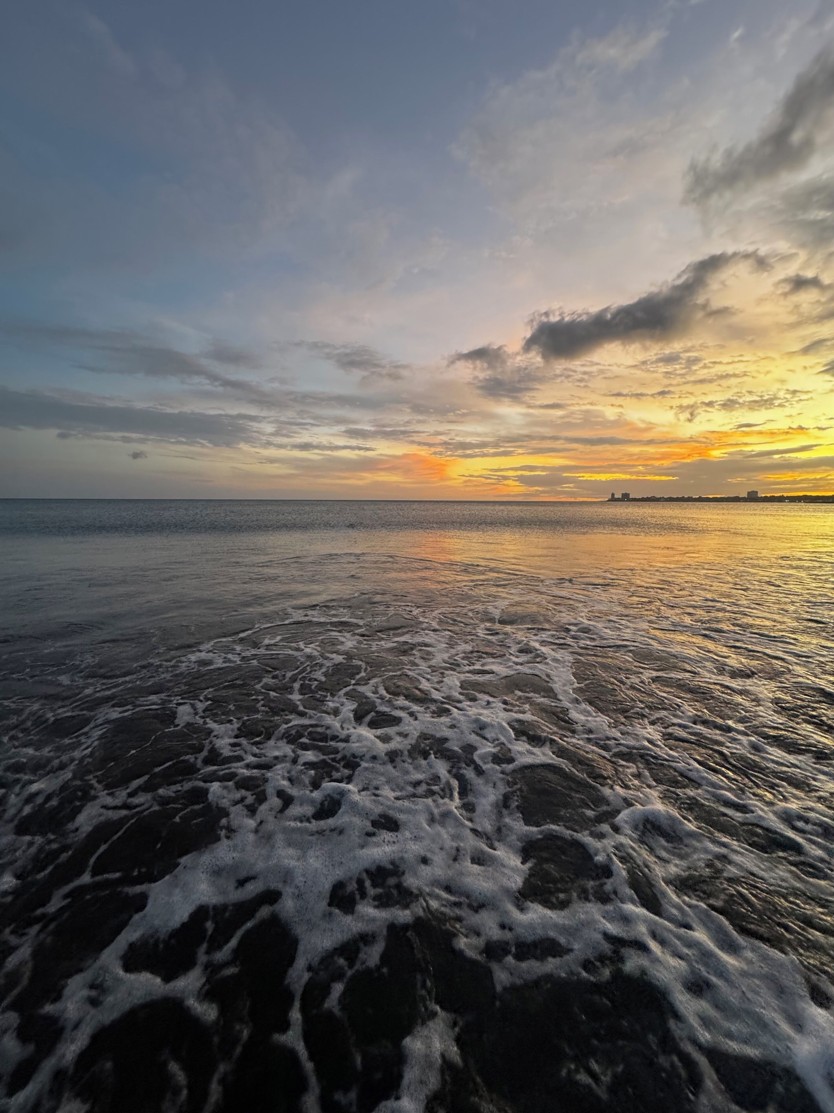 Una playa con olas y una puesta de sol al fondo.