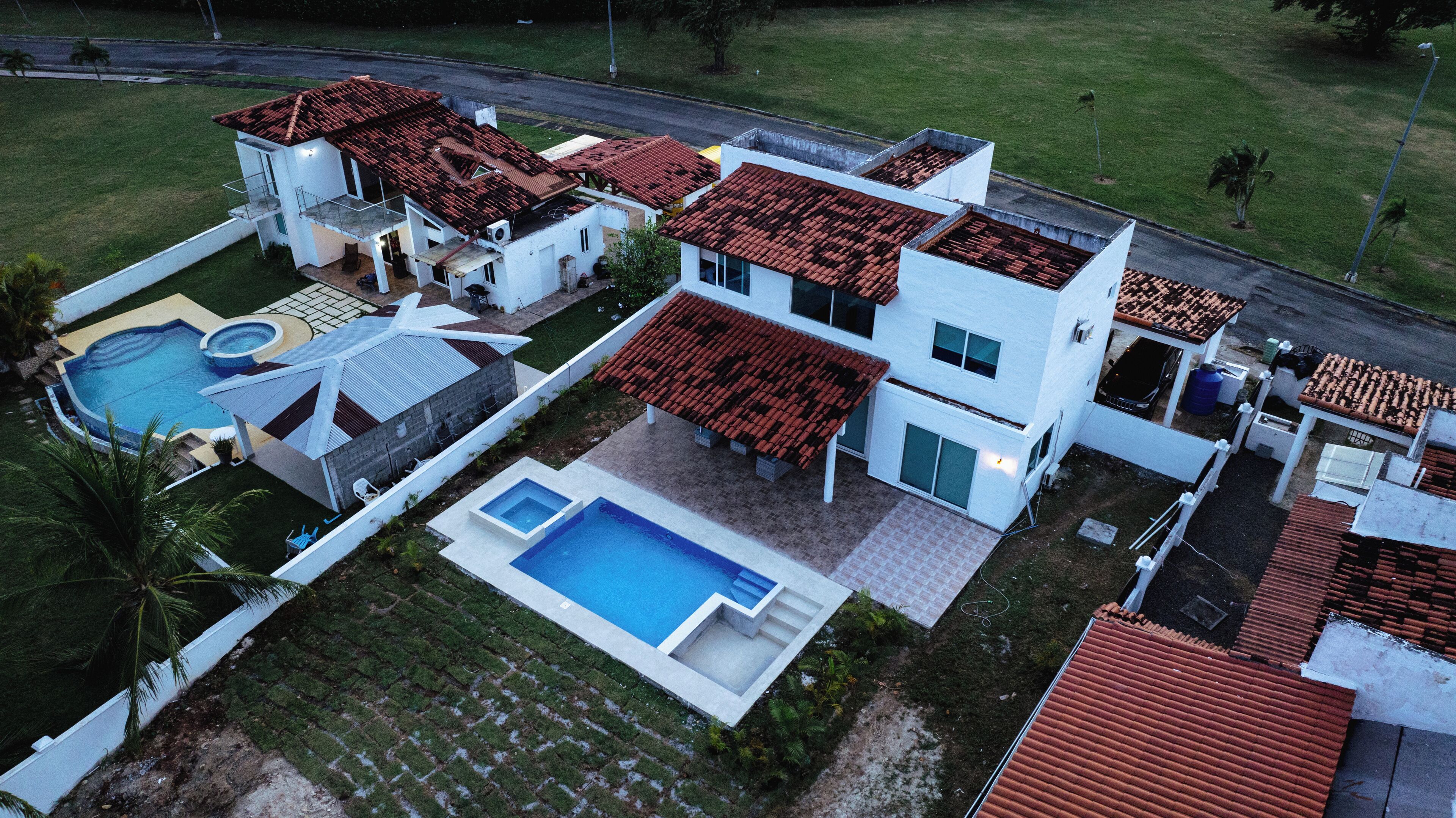 Une maison moderne à deux étages, dotée d’une piscine, d’un patio couvert et d’une pelouse bien entretenue.