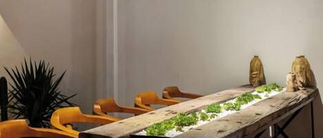 A long wooden table with chairs, a small plant, and two stone sculptures.