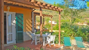 A covered patio with a table and chairs, surrounded by greenery and a view of a hillside. - Elbamar Lacona 2 - Elbamar Lacona 2 - Mono Classic (Capoliveri)