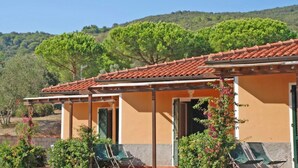 A building with a tiled roof, green shutters, and a balcony with a chair. - Elbamar Lacona 2 - Elbamar Lacona 2 - Mono Classic (Capoliveri)