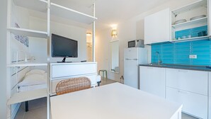Ett modernt kök med vita skåp, en blå väggbeklädnad bakom arbetsbänken och en inbyggd mikrovågsugn.