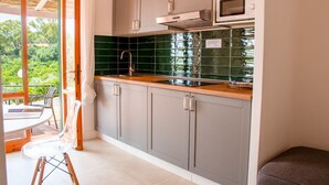Een kleine keuken met grijze kastjes, een houten aanrechtblad, een roestvrijstalen spoelbak en een magnetron.