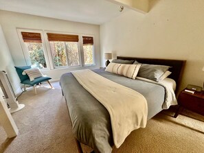 Un dormitorio con una cama grande, una silla y una ventana con persianas.