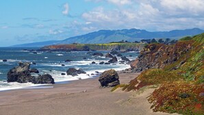 A beach with rocky outcrops and a view of distant hills. - Redwood Treehouse with Hot Tub (Guerneville)