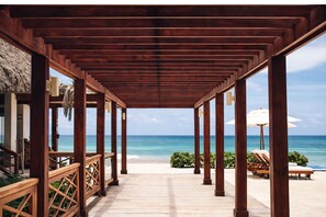 A wooden covered walkway leading to a beach with lounge chairs and umbrellas. - Penthouse at the Hard Rock Hotel (Punta Cana)