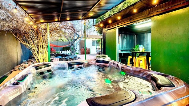 A hot tub area with a covered roof, surrounded by greenery and a small patio. - Arcadia Retreat + Resort Yard + Hot Tub + Detached Casita (Phoenix)