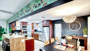A modern kitchen with stainless steel appliances, a wooden island, and a dining area with a chandelier. - Arcadia Retreat + Resort Yard + Hot Tub + Detached Casita (Phoenix)