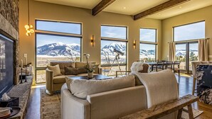 A spacious living room with large windows offering mountain views, a cozy seating area, and a rustic wooden bench. - Moonrise Ridge, a Luxury Mountain Home set in Paradise Valley (Emigrant)