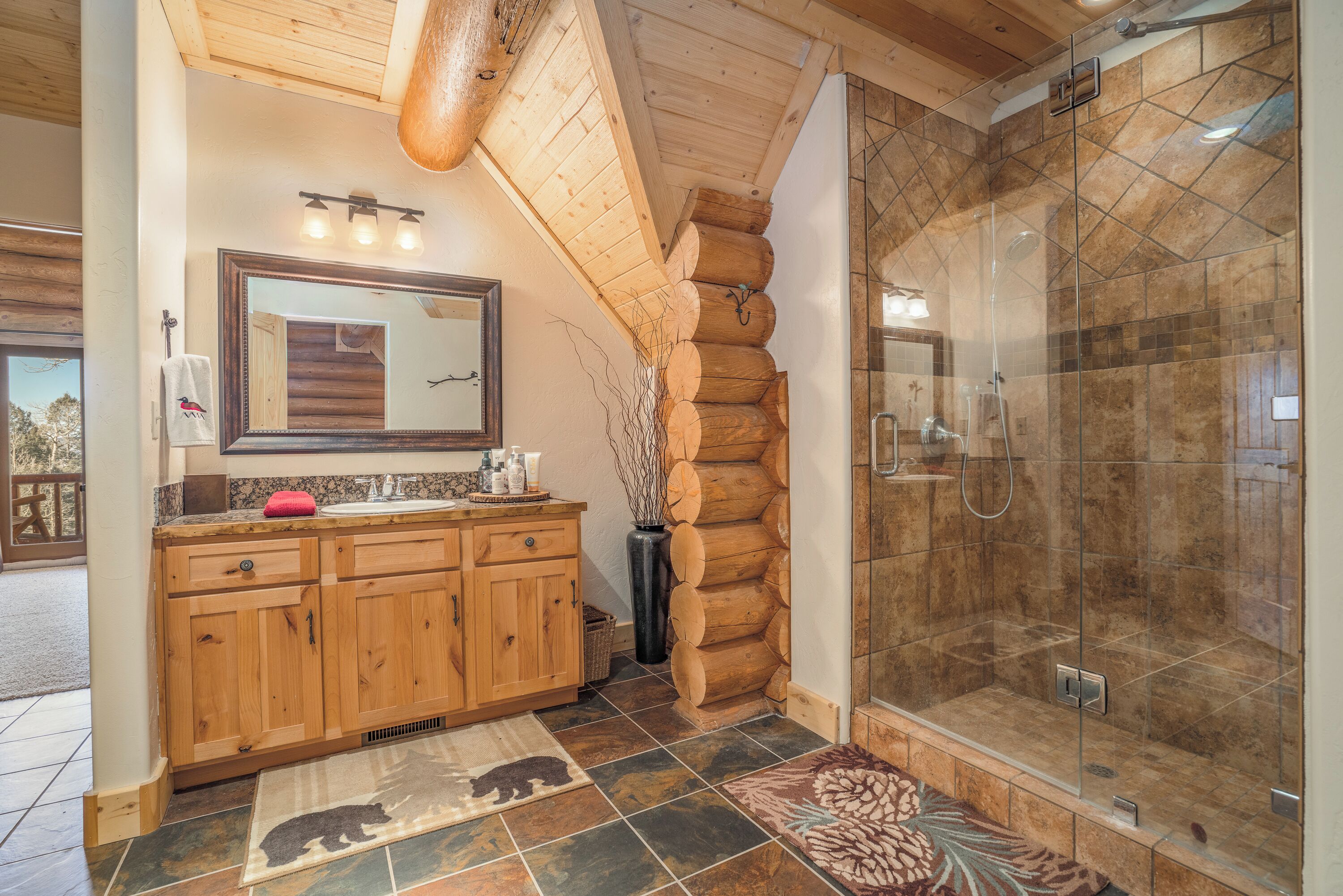 A bathroom with wooden cabinets, a large mirror, and a glass-enclosed shower.