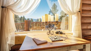 A wooden table with a book, candle holder, and a box of chocolates. - Custom high-end 3 bedroom log cabin sleeps 12. Located on the ski hill! (Angel Fire)