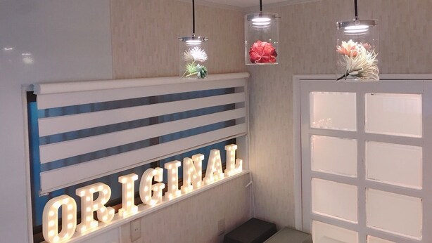 A room with a wall-mounted sign reading "ORIGINAL," overhead pendant lights, and a white door with frosted glass panels.