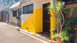 A residential building with a yellow and white facade, a gated entrance, and a small porch area.