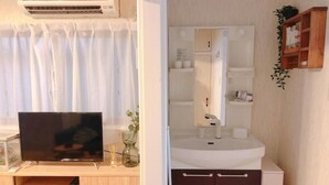 A compact room with a TV, a white sink, and a mirror.