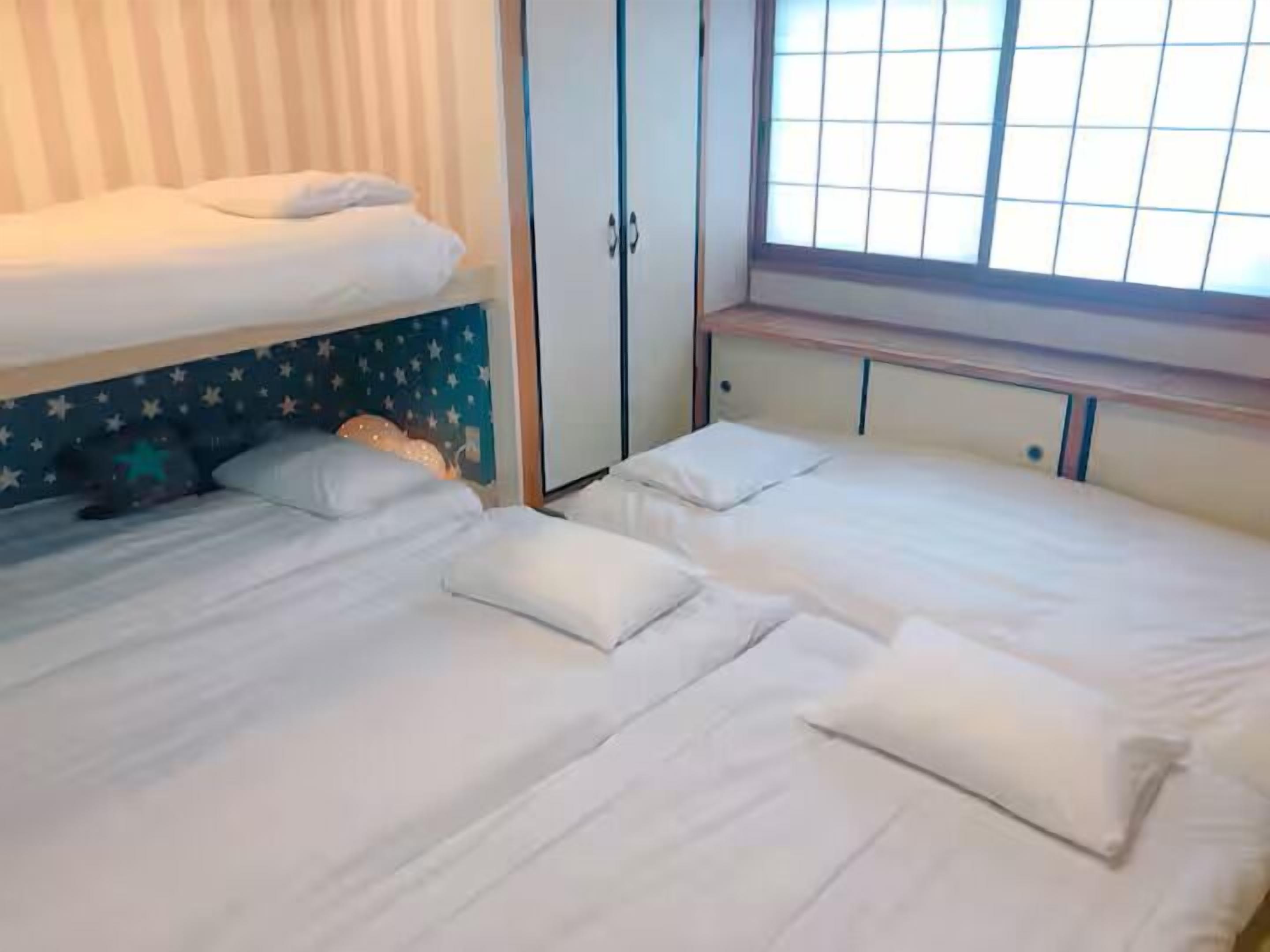 Una habitación con dos camas, un armario y una ventana.