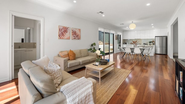 A modern living room with a sofa, coffee table, and a dining area with chairs. - St Georges Gem—Spacious & Well-located Family Stay (Saint Georges)