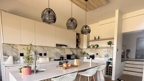 Une cuisine moderne avec un pare-feu en marbre, un plafond en bois et des luminaires suspendus.