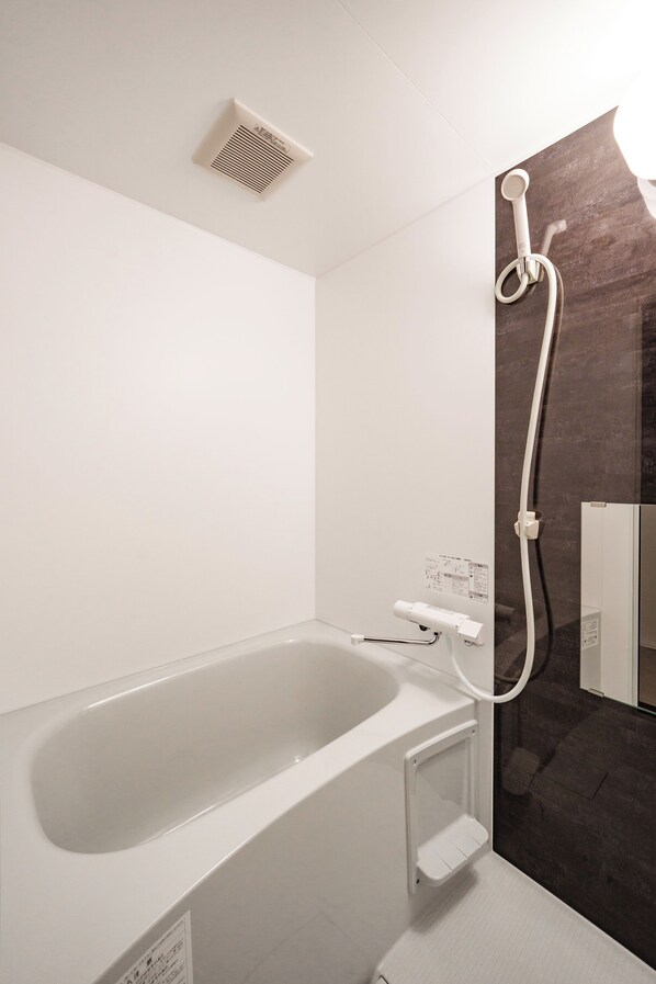 Une salle de bain moderne équipée d’une baignoire, d’une douche et d’un panneau de commande fixé au mur.