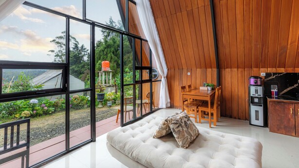A modern interior with a large glass window, a wooden ceiling, a dining area, and a kitchenette. - Villa Platinum 2 (Dieng Kulon)