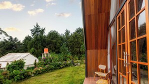 A modern building with large glass doors, a wooden exterior, and a well-maintained garden with a small shed. - Villa Platinum 2 (Dieng Kulon)