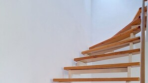 Een houten trap met witte wanden en een betegelde vloer.