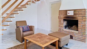 Een moderne woonkamer met een houten trap, een open haard, een bank en een salontafel.