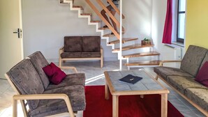 A modern living room with a wooden staircase, two sofas, a coffee table, and a red rug. - Green Valley Park Stárkov 9 by Interhome (Stárkov)