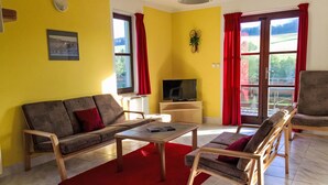A living room with a sofa, chairs, a coffee table, a TV, and a red rug. - Green Valley Park Stárkov 9 by Interhome (Stárkov)