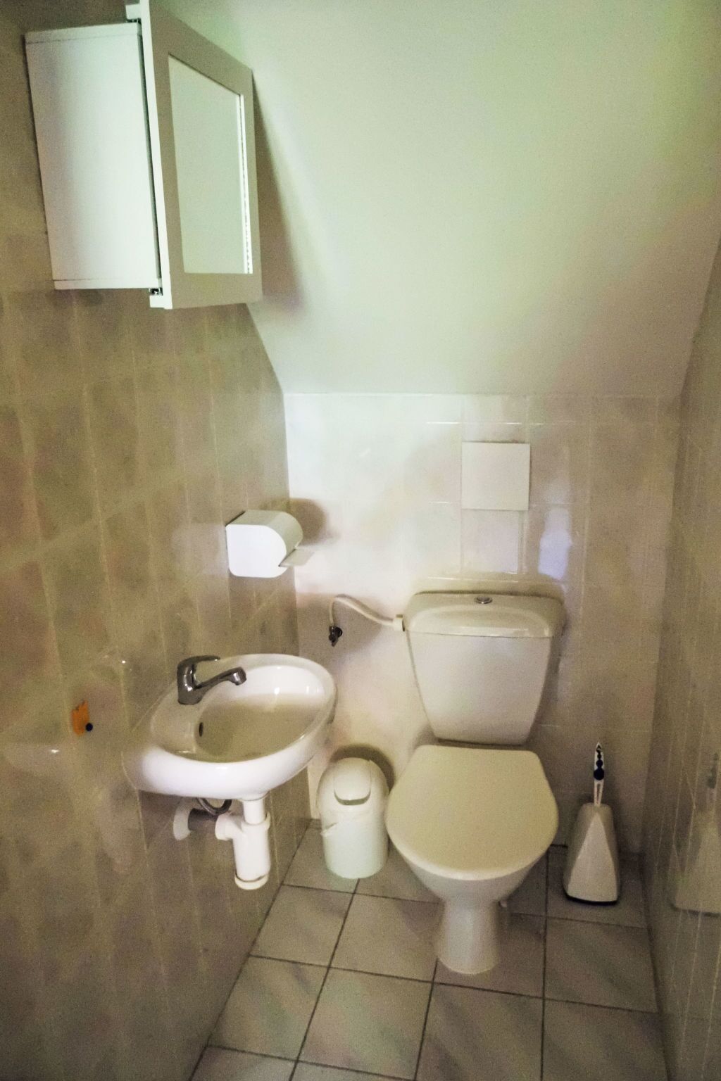 A small bathroom with a toilet, sink, and a cabinet above the sink.