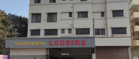 Ein mehrstöckiges Gebäude mit einem Schild für 'SAI PAVILION LODGING' und einer geschlossenen Garagentür.