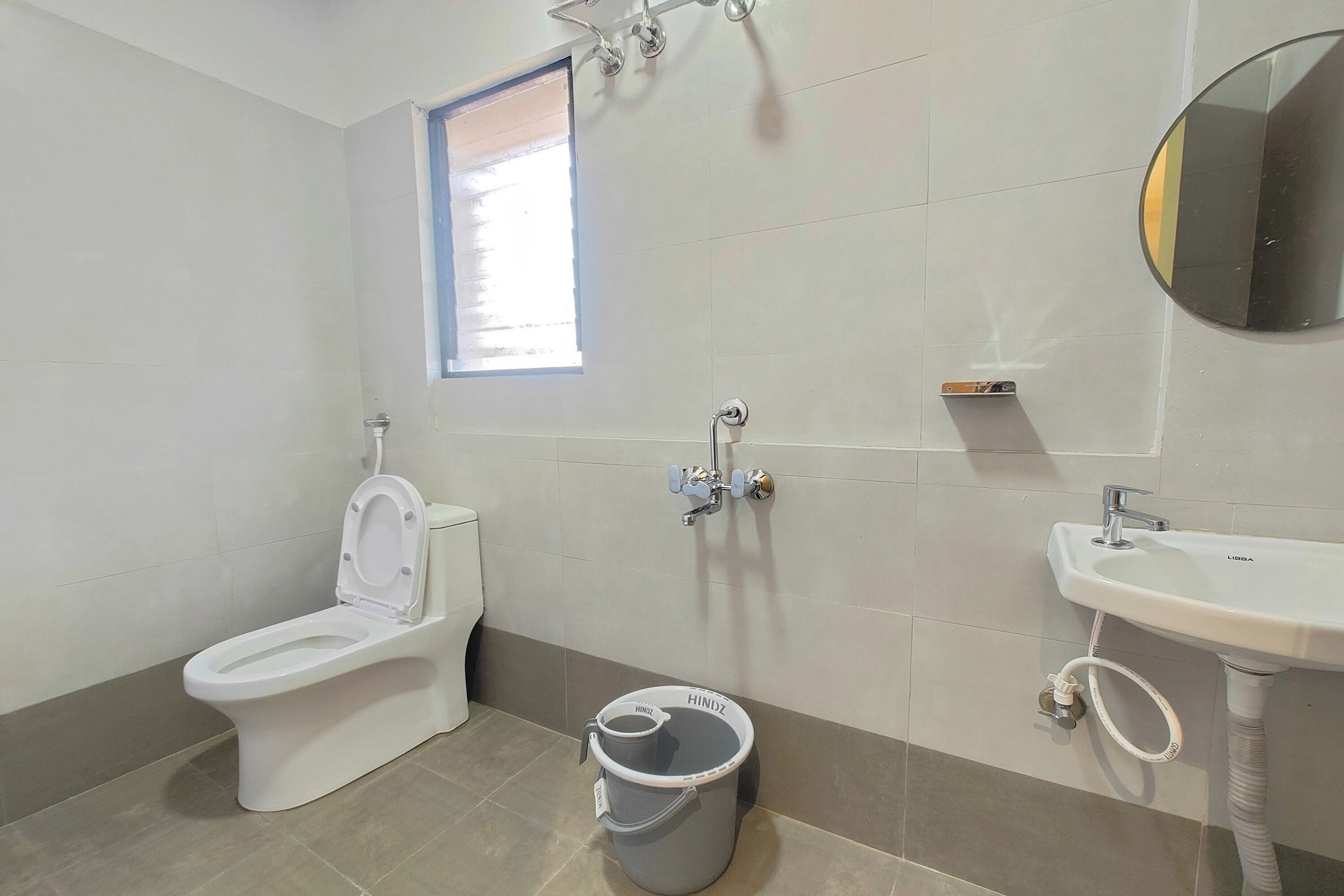 A bathroom with a toilet, bidet, sink, and a trash bin.