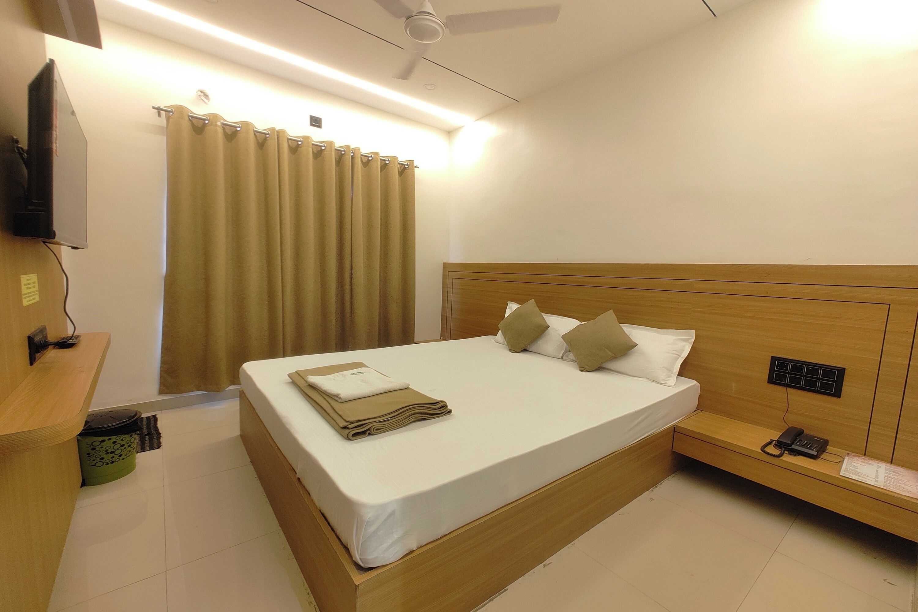 Ein Hotelzimmer mit einem Bett, einem Schreibtisch, einem Telefon und einem Deckenventilator.