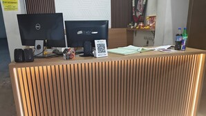Un comptoir d’accueil équipé de deux écrans, d’un code QR, d’un téléphone et d’un petit haut-parleur.