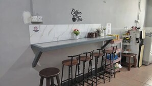 A kitchen with a marble countertop, bar stools, a coffee-themed wall decal, and a refrigerator. - Confidence Motel (Langkawi)
