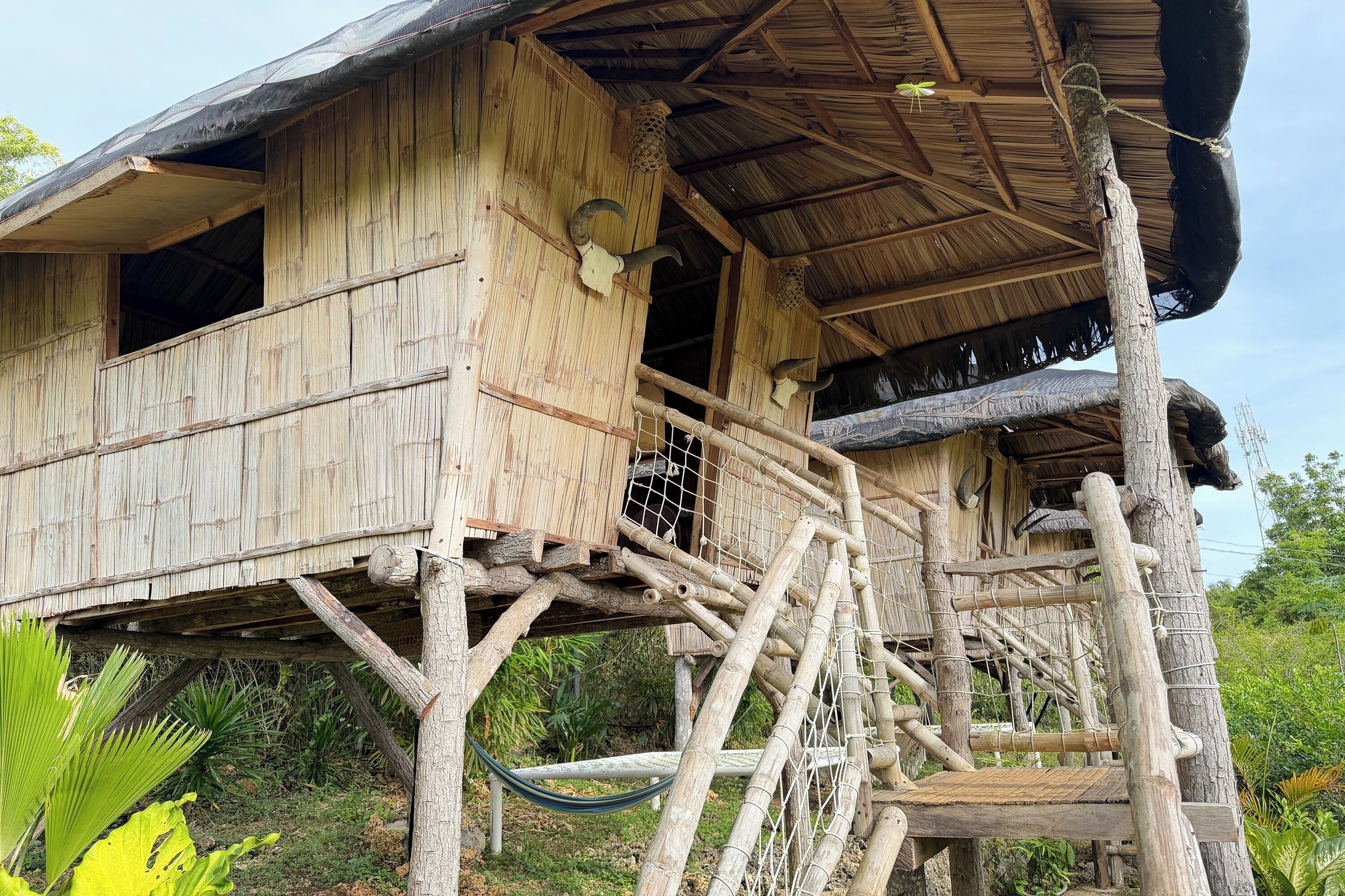 A wooden structure with a thatched roof, elevated platforms, and a rope ladder.