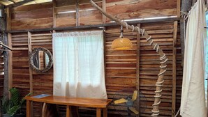 Una habitación rústica de madera con una mesa de madera, un ventilador, un espejo y una lámpara colgante.