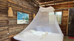 Una habitación de cabaña de madera con una cama, un cuadro y un mosquitero.